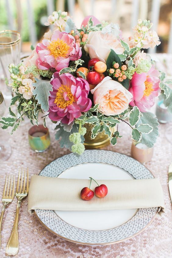 wedding decoration centrepiece with flowers and cherries and a cherry on the plate