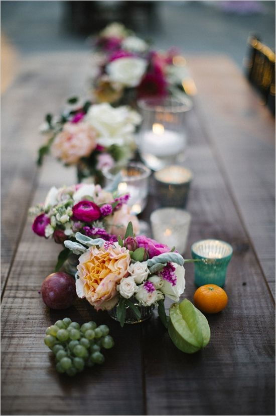 wedding decoration centrepiece with tealights candles fruit and handmade jars with freshly cut flowers