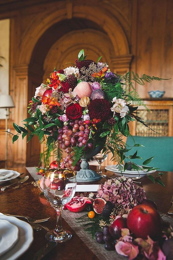 wedding decoration centrepiece with a composed with flowers and fruits, pomegranate, grape and apple