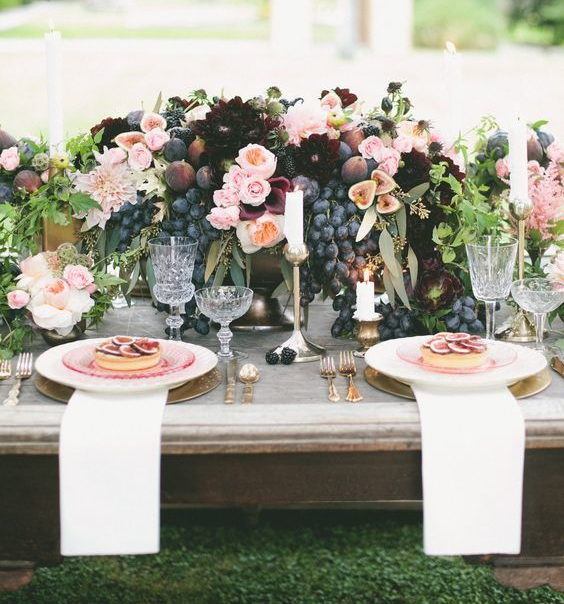 wedding decoration centrepiece with black grapes and figs, burgundy and pink flowers and bronze vases
