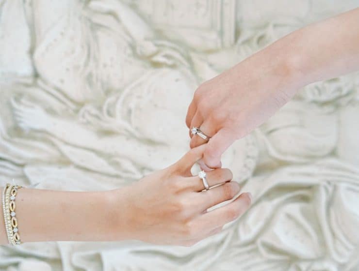 Ένα ζευγάρι κράταει χέρια, με βέρες από το κατάστημα Yiotis Jewellery.